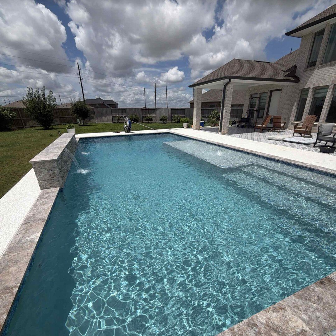 Crystal-clear pool with stone coping and Cypress home